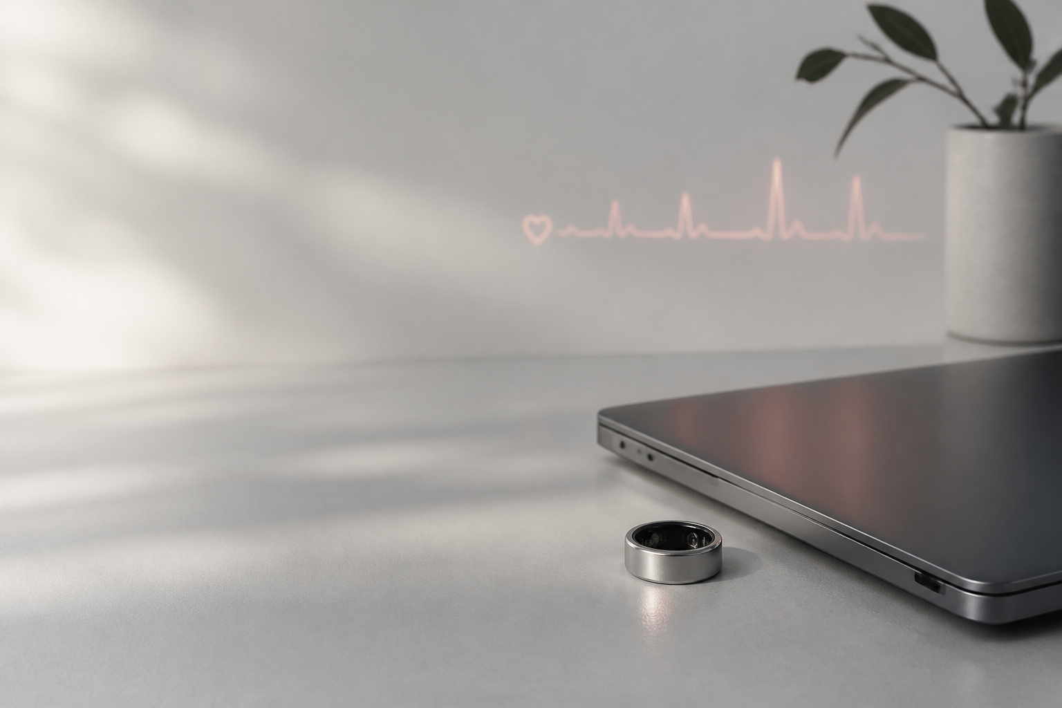 A smart ring beside a laptop on a calm workspace desk.